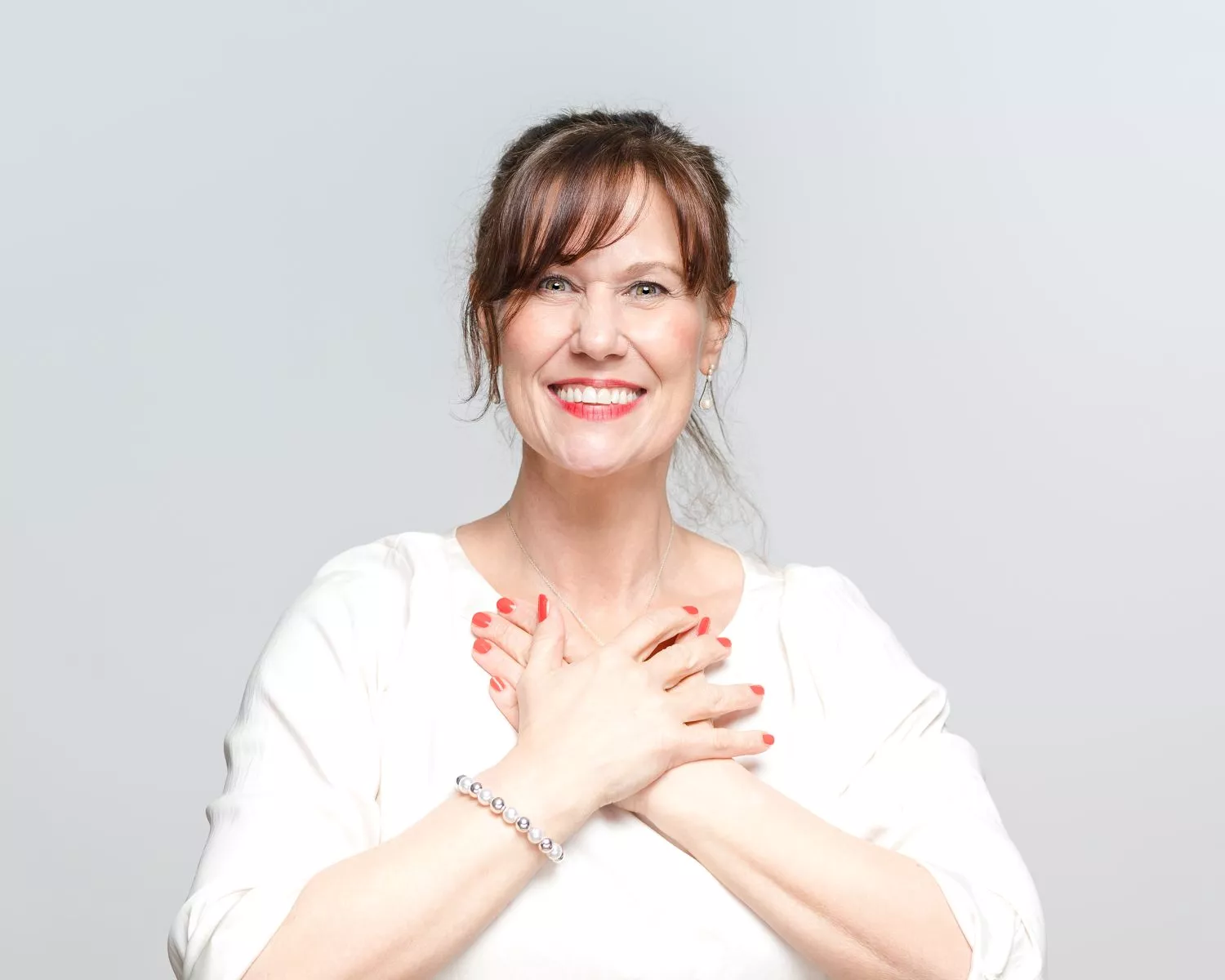 Patricia, dich anlächelnd, beide Hände verschränkt vor der Brust