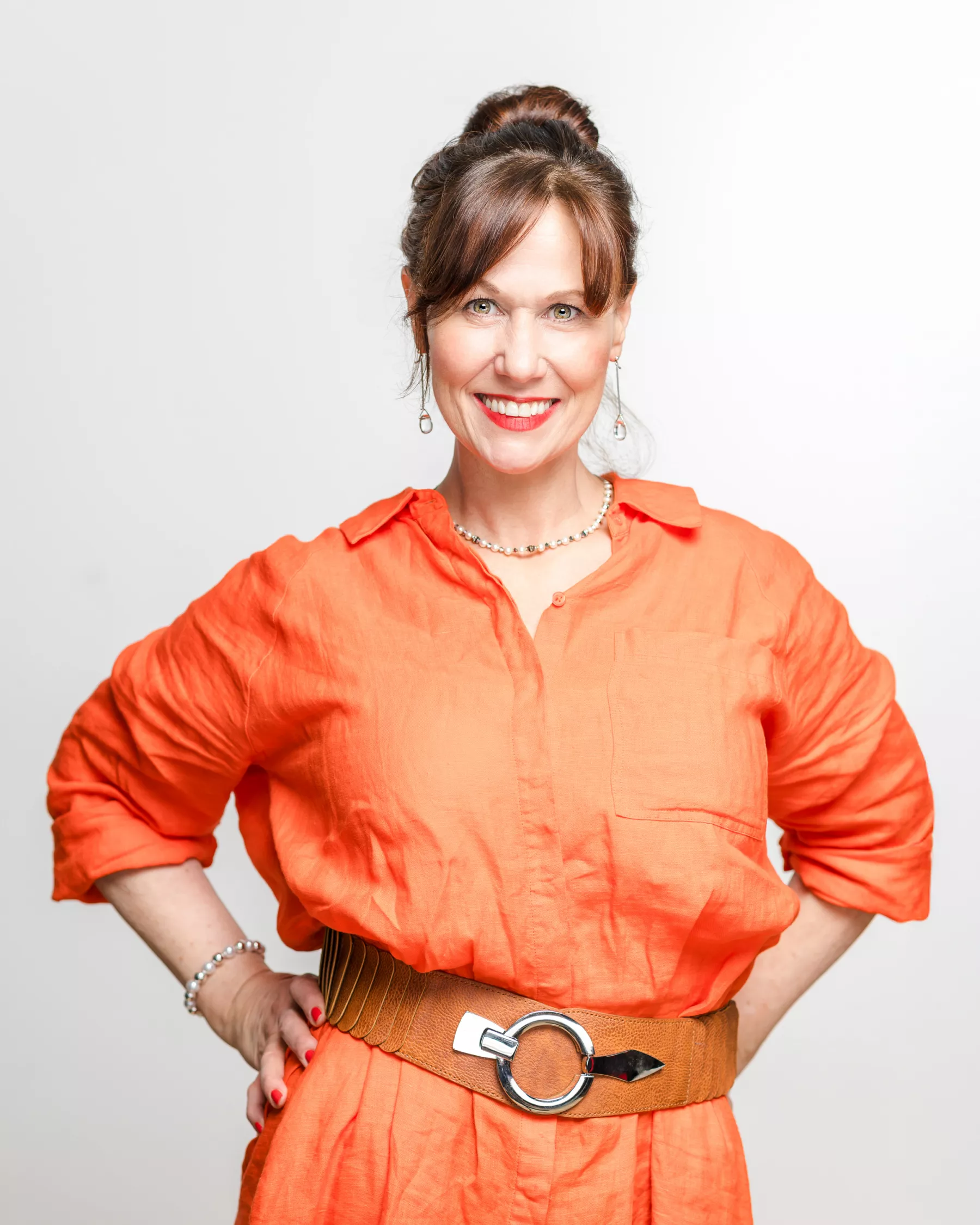 Patricia, dich anlächelnd, Hände in die Hüften gestützt